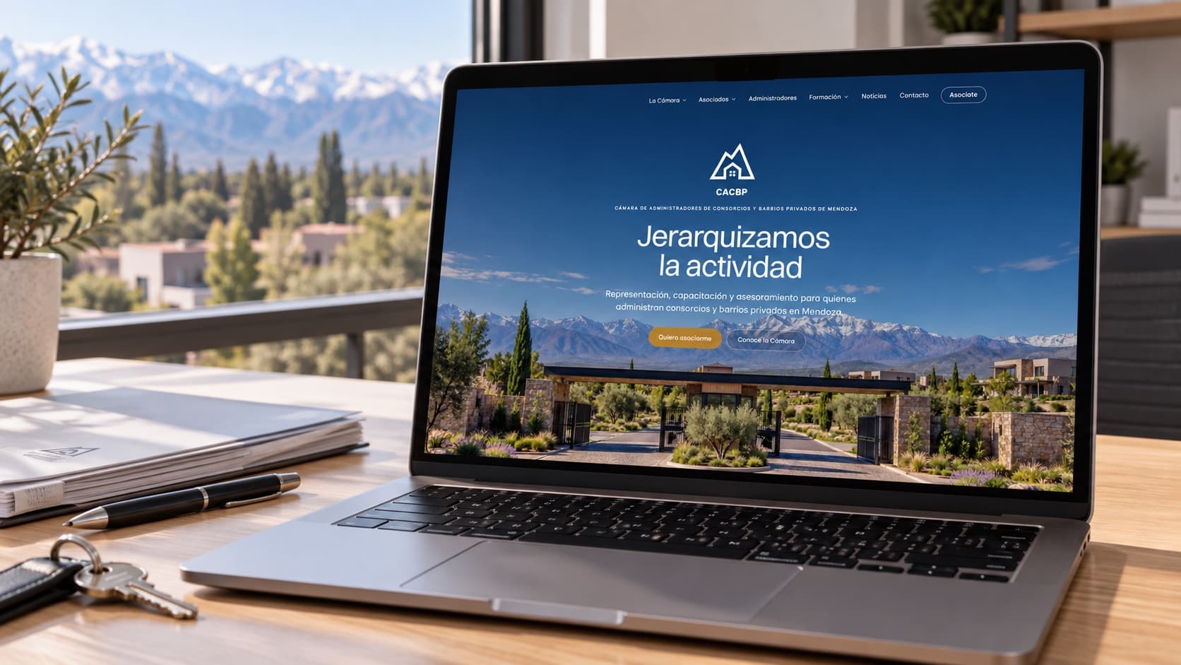 Portátil sobre un escritorio de oficina mostrando el sitio de la Cámara de Administradores, con la cordillera de Mendoza en la ventana